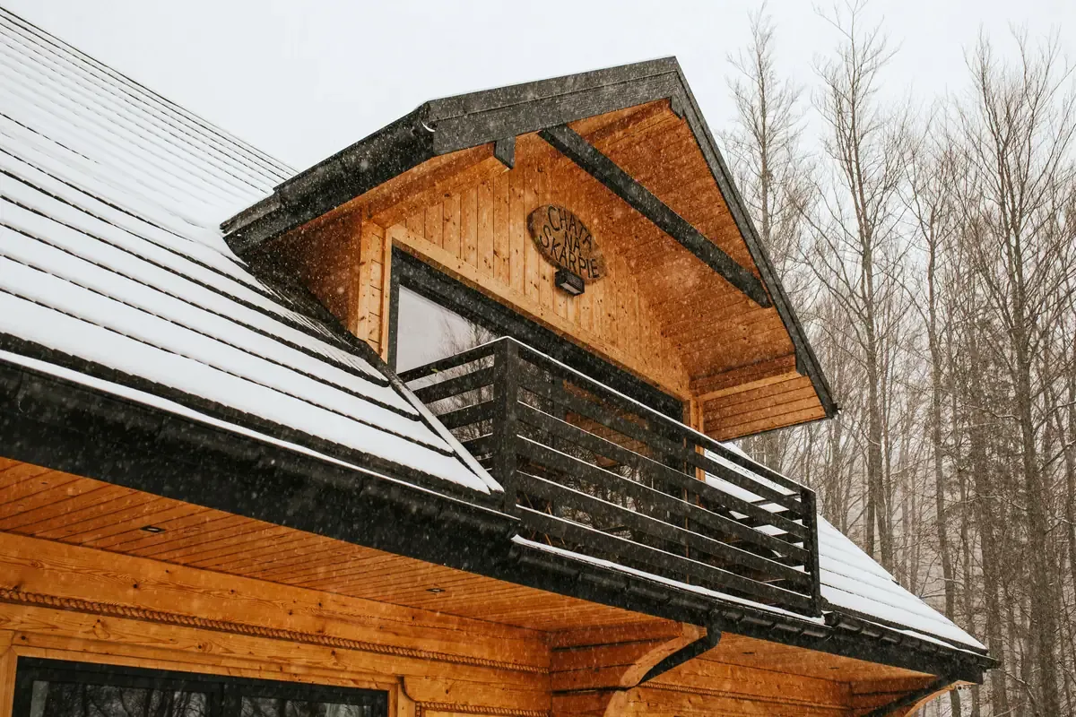 Drewniany balkon i ośnieżony dach domku góralskiego w Szczyrku