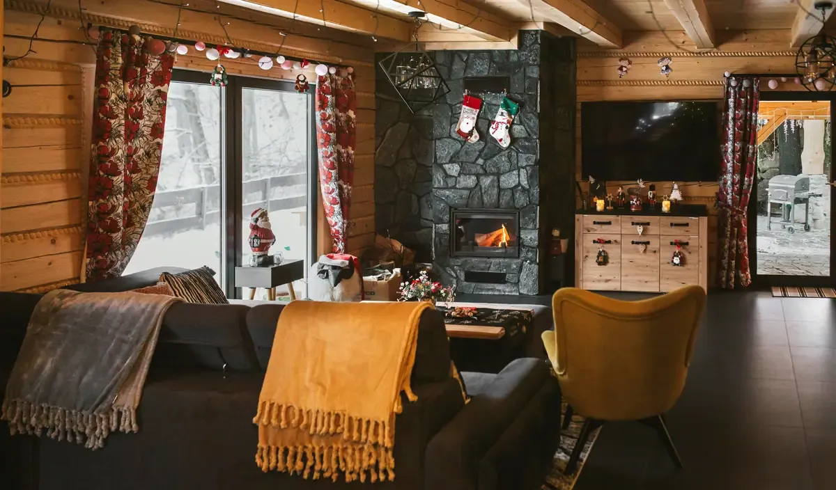 Przytulny salon z kominkiem i narożną kanapą zimą, domek w Szczyrku